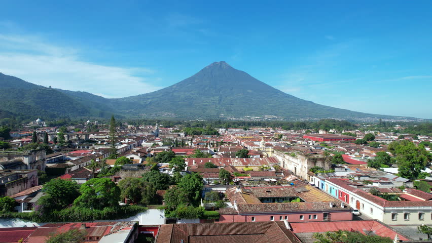 Aerial view of Antigua Guatemala by DJI air2s drone above the city, revealing beautiful architecture and landscape of the city. sunny sky volcano, Fuego, in the background. | Shutterstock HD Video #1099543881