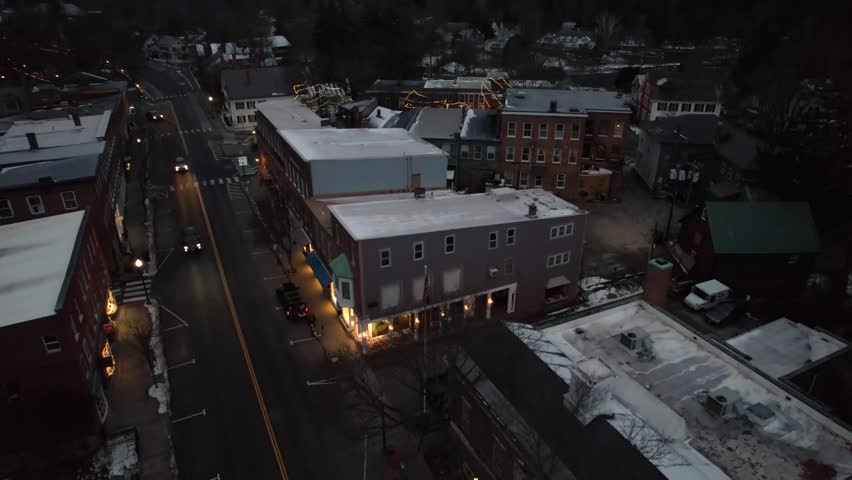 Early morning rising aerial, town of Woodstock, Vermont with cars passing by on cold winter day