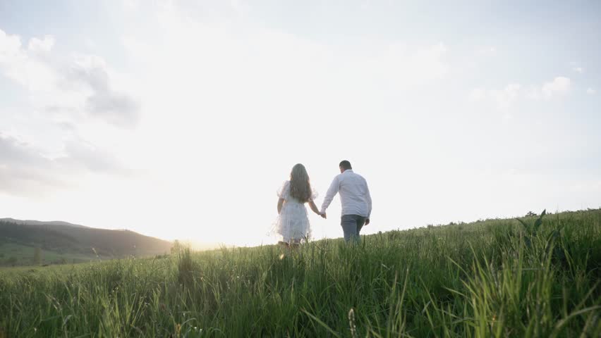 On Valentine's Day, a boy and a girl in love walk, hug, relax in nature. Happy couple having fun against sunset background. Holding hands while watching the sunrise. | Shutterstock HD Video #1099548681