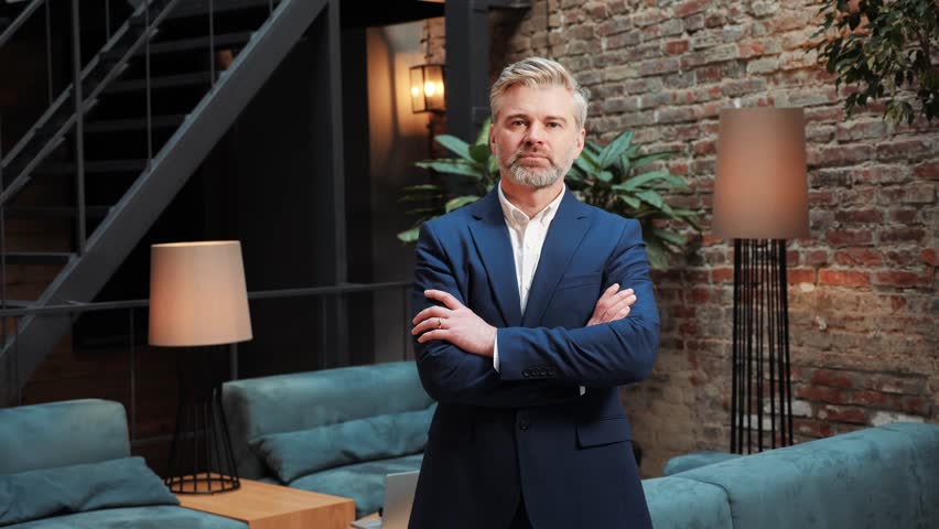Portrait of adult successful businessman with a beard is looking at the camera with folded hands. Financial expert, lawyer, banker posing in the negotiation room. Headshot business male portrait. | Shutterstock HD Video #1099550901