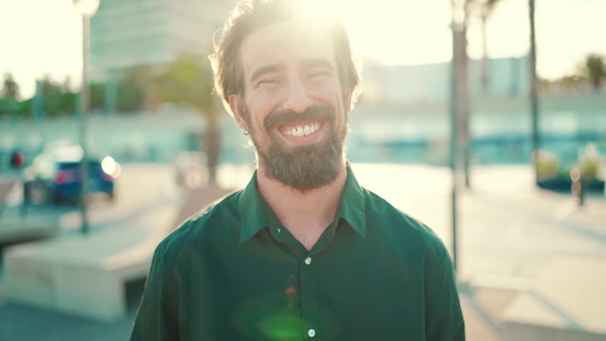 Closeup portrait of smiling man with a beard on an urban city background. Frontal close-up of happy young hipster male looking at camera | Shutterstock HD Video #1099551065