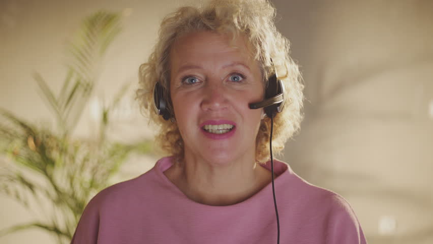 Woman having video conference call. Looking at camera and speaking. Beautiful blonde female wearing headset. | Shutterstock HD Video #1099551309