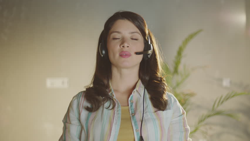 Happy young woman wear headset communicating by conference call at modern office | Shutterstock HD Video #1099551319