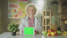Mature female gynecologist sitting desk holding tablet with different fruits and vegetables - Powered by Shutterstock - Get 15% off with code: PIKWIZARD15