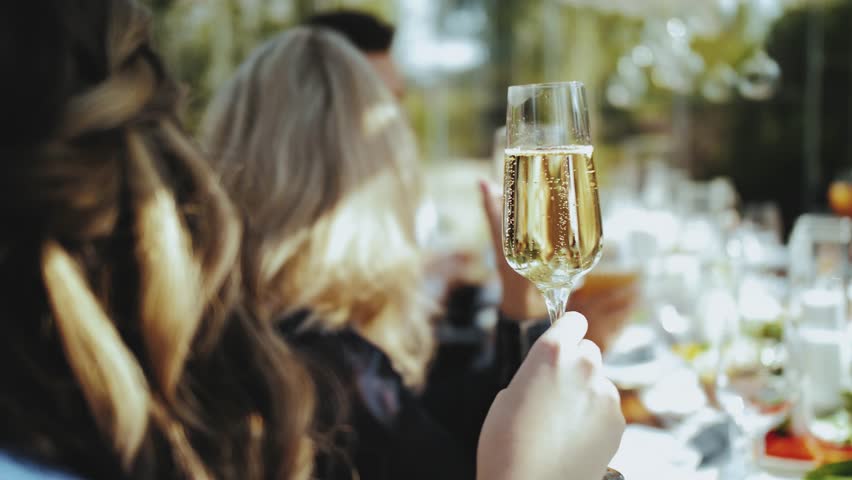 Close-up female holding glass of champagne at the wedding, bubbles in a champagne glass. Beautiful girls have fun on a party slow motion. | Shutterstock HD Video #1099552033