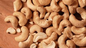 Cashew nuts from above. Close up 4k video with cashew on a wooden plate, pan camera movement.