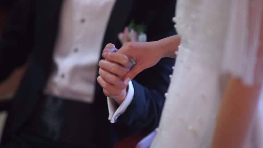 The hands of a beautiful couple of a man and a woman touch at a solemn wedding ceremony | Shutterstock HD Video #1099556553