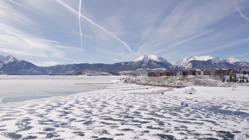 Frozen Lake Aerial Drone Footage. Dillon Reservoir Facility and Rocky Mountains in Background. Colorado. Daytime. Tracking push in.