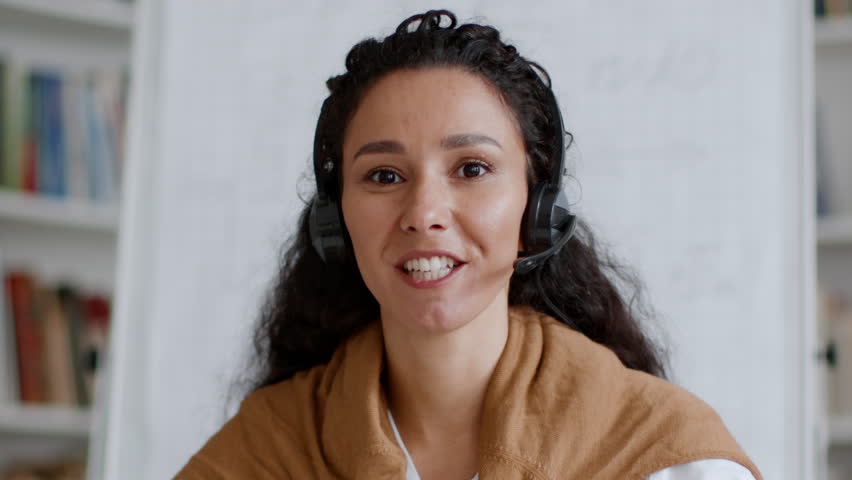 Online communication. Webcam pov portrait of young professional middle eastern woman manager in headset with mic talking to camera, explaining topic to interlocutor | Shutterstock HD Video #1099560363