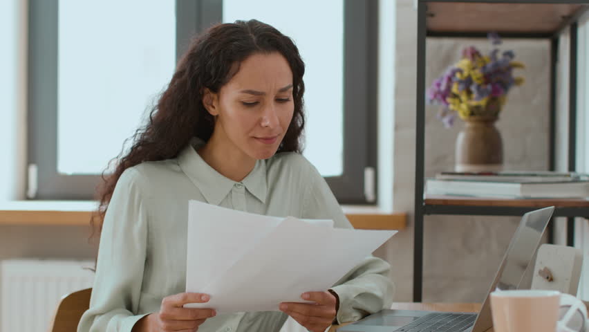 Remote work concept. Young busy middle eastern business lady checking documents and filling online report on laptop, sitting at home office, free space | Shutterstock HD Video #1099560413