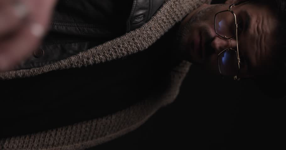 close up of sexy bearded man indicating with hand and being cool, looking to side and adjusting jacket