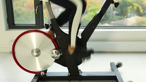 Closeup of spinning wheel on exercise bike at home on spin bicycle fitness workout. Woman training on stationary bike watching online video class for exercising cardio - Powered by Shutterstock - Get 15% off with code: PIKWIZARD15