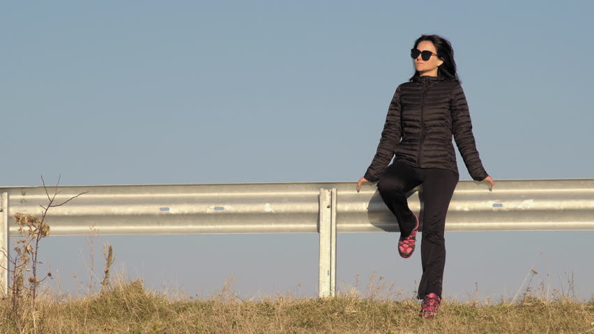 Attractive mature woman sitting by the road alone stopping hitchhiking