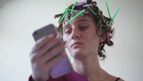 Hispanic teen girl with afro curly hair style with plastic straws surfing on mobile smartphone