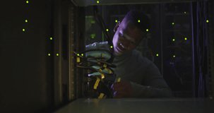 Animation of binary coding over african american male it engineer and computer servers. Global computing and data processing concept digitally generated video.