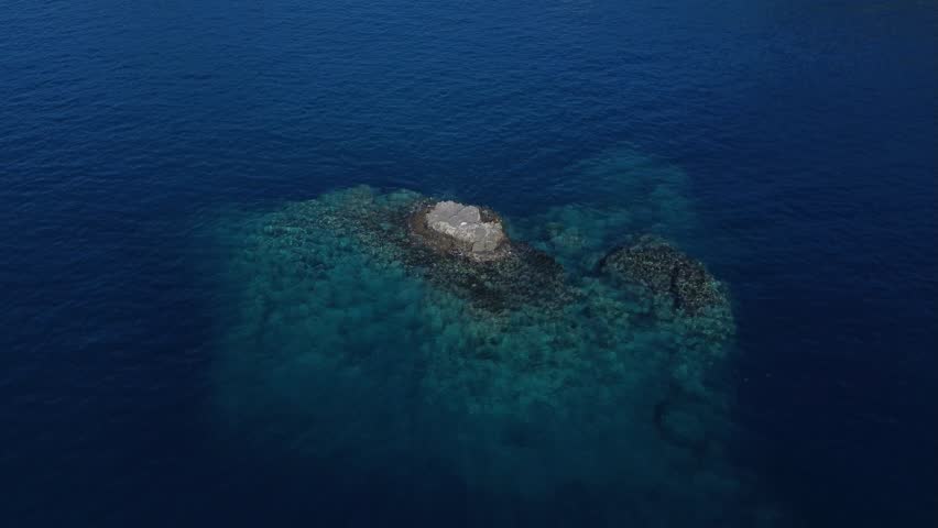 A very small rock island just off the coast in deep water. | Shutterstock HD Video #1099567039