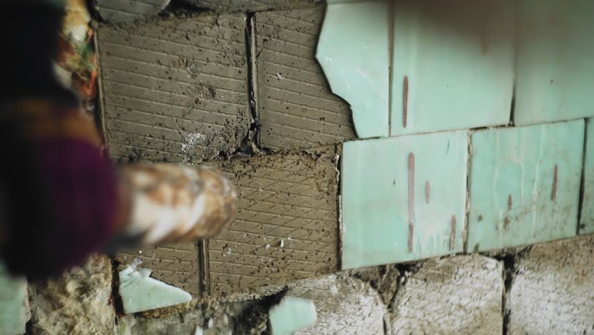 A man breaks tiles in an old abandoned building. He hits the wall with a bat | Shutterstock HD Video #1099569179