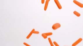 Bright orange baby carrots falling on white backdrop in slow motion - Powered by Shutterstock - Get 15% off with code: PIKWIZARD15
