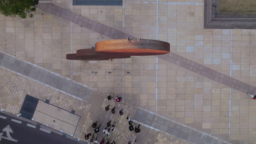 top down abstract of a sculpture made of three circles and a group of people passing under it in the Habima Square - Tel Aviv, Israel