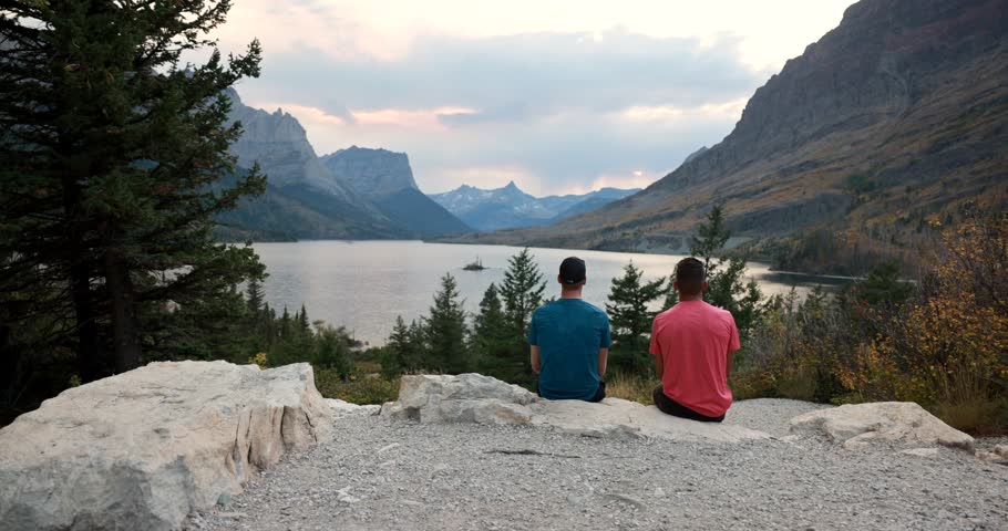Glacier National Park, Montana USA - Time Lapse with 2 people sitting on a rock as the clouds and tourist come to photograph St Mary lake and wild good Island