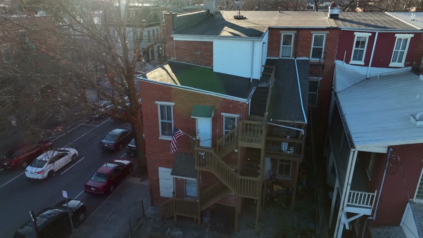 Aerial view of back of city home. American flag waving beside fire escape steps on old brick house in urban area in USA.