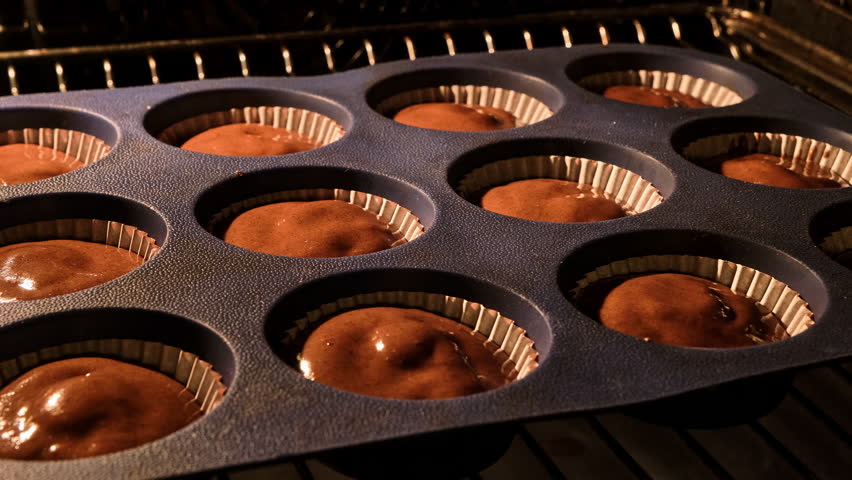 Chocolate muffins. Baking in oven. Time lapse footage of cooking brown cupcakes. Homemade bakery concept. Growing cupcakes. Close-up in 4k, UHD Royalty-Free Stock Footage #1099576001