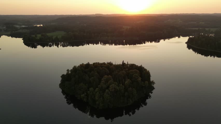 Heart round shaped island on a lake with sunset. Aerial view of of islands on a blue lake in Sweden, Finland, Estonia. Blue lake, islands and green forest from above on a sunset summer evening.
