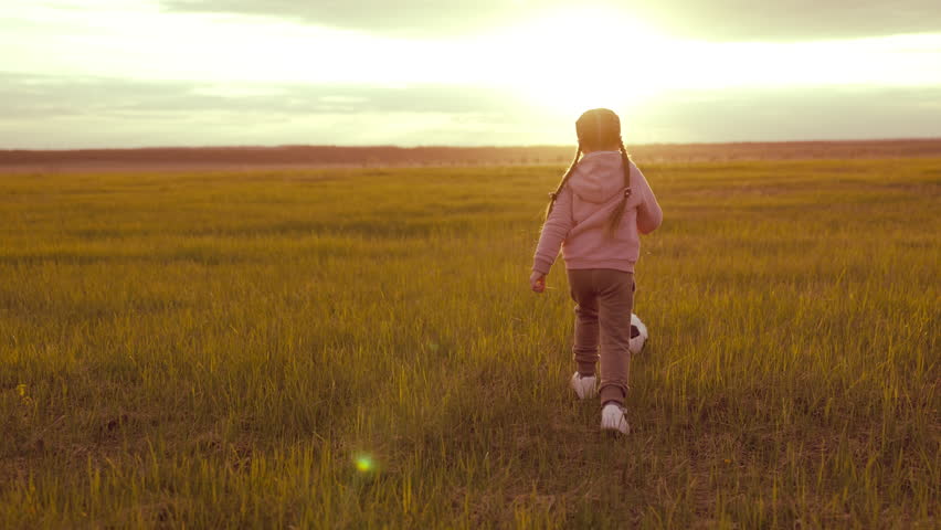Child runs across field playing soccer ball. chidhood dream. Happy family. child dream being football player. kid play game football sunset. children's running outdoors field with ball. girl daughter | Shutterstock HD Video #1099580185