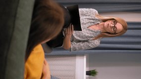Woman psychologist talks and helps girl. recording important studies in tablet, view from back or behind. psychology, mental health concept of people. Vertical video. Reception with psychotherapist.