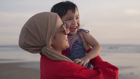 Happy Modern Muslim Southeast Asian Indonesian Family Enjoying Sunset Together on The Beach. Silhouette of Father Mother and Child in Slow Motion.の動画素材