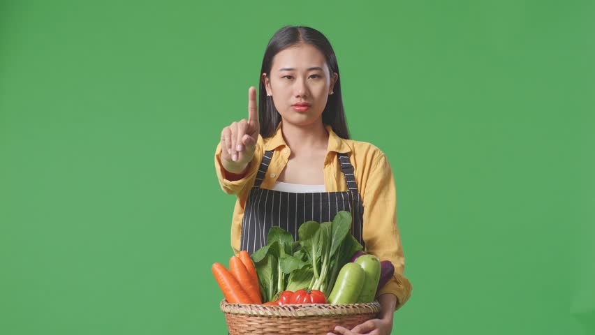 Asian Female Farmer With Vegetable Basket Showing Stop, One Finger Gesture, Taboo Sign, Standing On Green Screen In The Studio
 | Shutterstock HD Video #1099588271