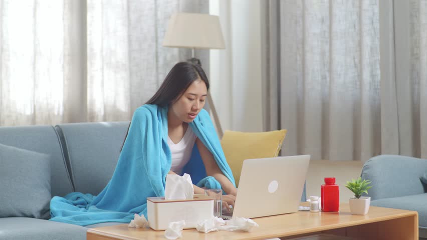 Sick Asian Woman With Blanket Sitting On Sofa Works On A Laptop Computer In The Living Room At Home
 | Shutterstock HD Video #1099588421