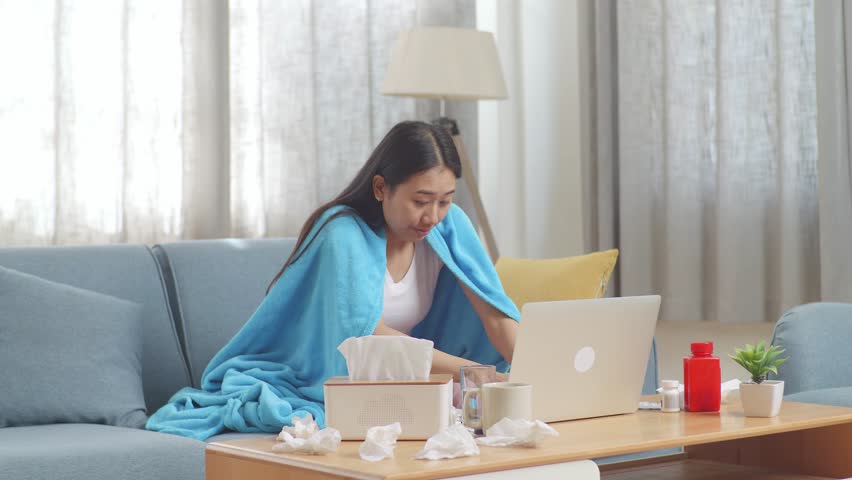 Sick Asian Woman With Blanket Being Cold While Sitting On Sofa Works On A Laptop Computer In The Living Room At Home
 | Shutterstock HD Video #1099588423