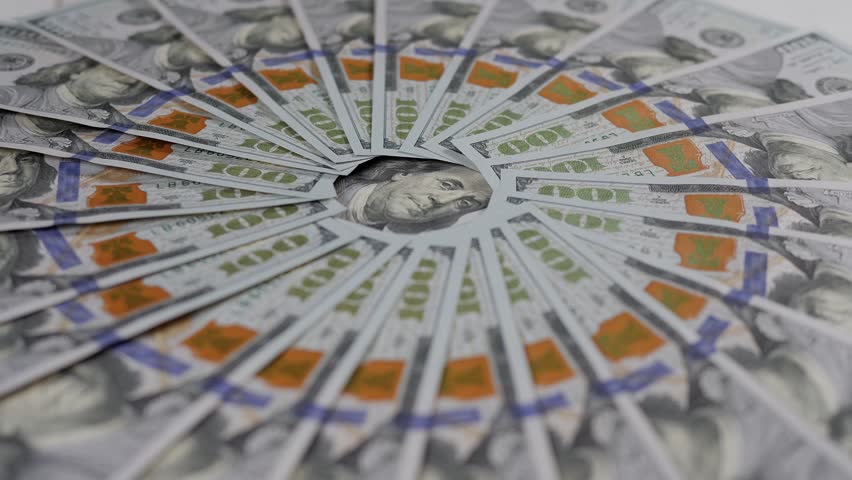 A lot of hundred-dollar bills are lying around and slowly rotating. The concept of business, finance and money.