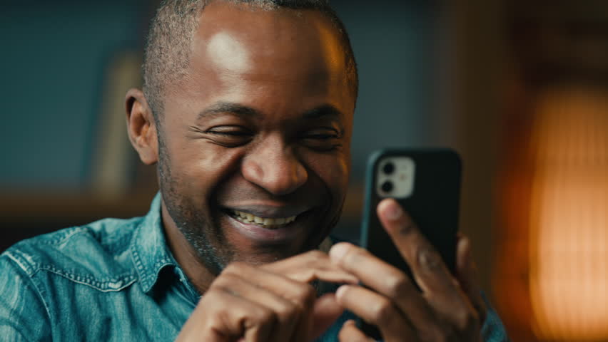 Close-up surprised mature african american man holding smartphone reading good news in Internet excited ethnic male winner win in mobile online application on phone get great offer celebrate victory | Shutterstock HD Video #1099590773