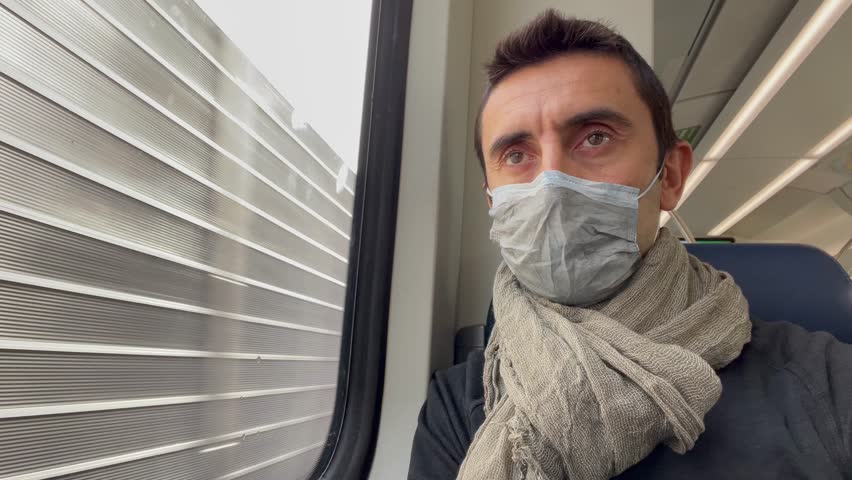 Young man with face mask traveling on train by metal fence area. Male passenger on window seat during Covid-19 pandemic season, health care, safety protocols restrictions concepts | Shutterstock HD Video #1099591573