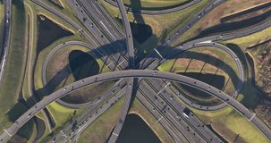 Aerial drone video of Knooppunt Ridderkerk, a busy intersection in the Netherlands with roads converging from different directions. Cars, trucks and other vehicles are seen moving along the roads.