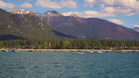 Many sailing boats floating on the water of Lake Tahoe with Sierra Nevada Mountains and South Lake Tahoe in the background. 4K UHD video.