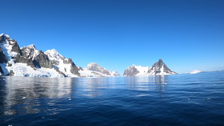 Antarctica landscape water surface and snow-capped mountains time lapse. Amazing calmness characteristic of Antarctica is given by clear blue sky. | Shutterstock HD Video #1099593015