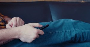 Slow motion 4k footage of a male hand hand holding the TV remote control smart television. Internet online cinema - smart tv channel surfing.