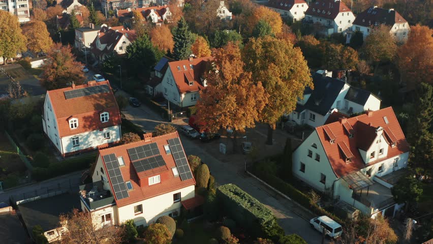 Aerial view of a complex of country houses with solar panels on roofs in a modern European city. Solar panels on the roofs of private buildings to generate electricity using the sun.  Royalty-Free Stock Footage #1099597197