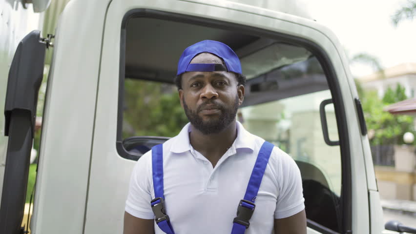 Black employee worker with a truck car moving house for customers, delivering boxes with uniform. Vehicle transportation. Shipping and packaging business occupation service company. People lifestyle.