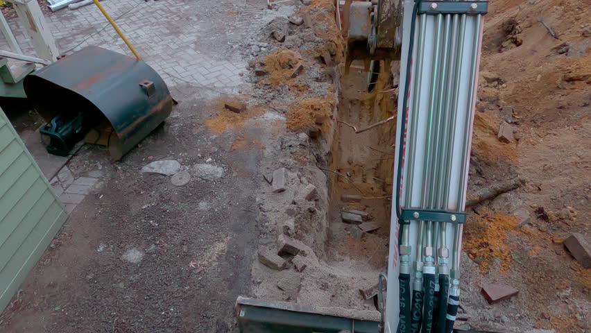 A bucket of the excavator getting soil from the ground during the winter time. Top view