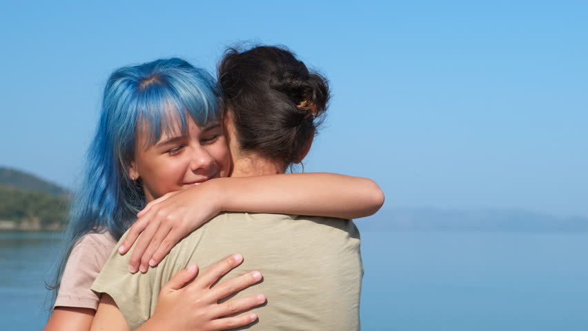 Enjoy parents vacation among sea. A teen embrace with her mother on sunny beach. A concept of child and parents sea vacation. | Shutterstock HD Video #1099606129