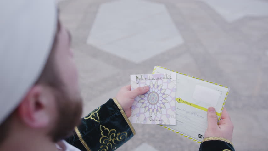 Mullah prepares invitation to visit gracious UNESCO heritage. Bearded man stands on vast square of White Mosque in settlement Bolgar