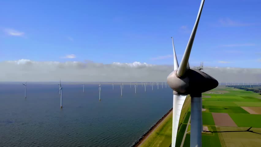 Offshore windmill park green energy with clouds and a blue sky, windmill park in the ocean aerial view with wind turbine Flevoland Netherlands Ijsselmeer | Shutterstock HD Video #1099607539