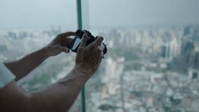 Male Hands With Digital Camera Taking Photo Of City Skyline Of Bangkok Through Glass Window Of Baiyoke Tower In Thailand. close up