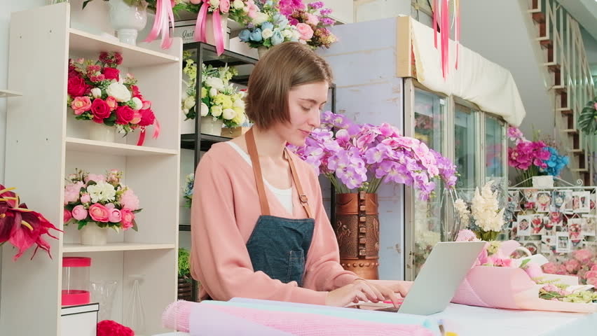 One young Caucasian florist owner works with laptop, website arrangement for online business flora service in colorful flower shop store with beautiful bunch of blossom, e-commerce SME technology. | Shutterstock HD Video #1099611361