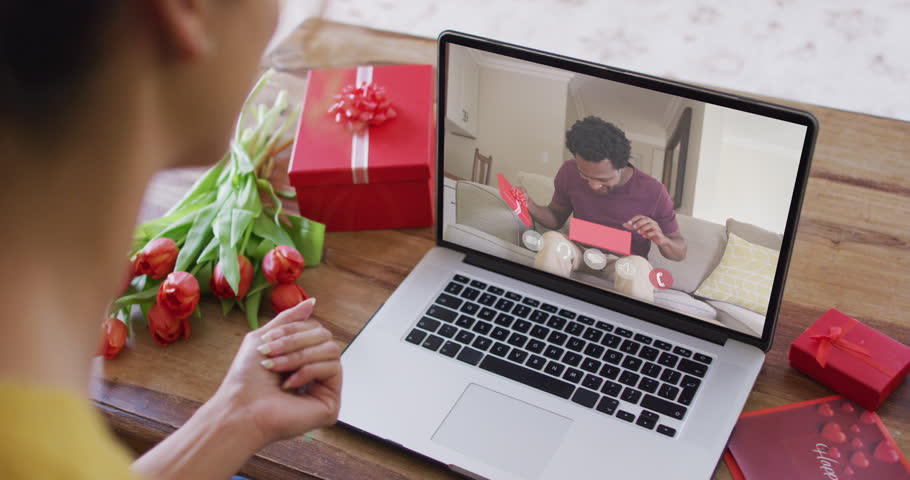 Happy african american man opening gift and making valentine's day video call on laptop. valentine's day celebration, romance and communication technology. | Shutterstock HD Video #1099612133
