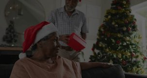Animation of merry christmas text over senior african american couple wearing santa hats. Christmas, tradition and celebration concept digitally generated video.